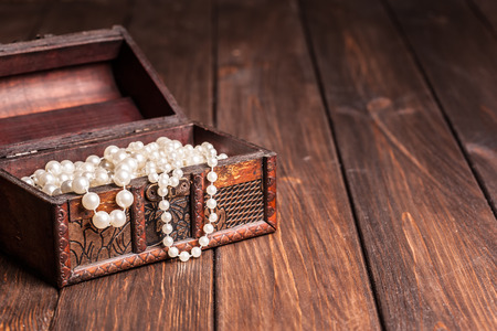 old treasure chest with pearl necklaces standing on wooden tableの写真素材