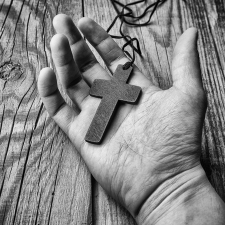Cross in hand on wooden backgroundの写真素材
