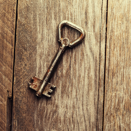 old keys on a brown wooden background, close up