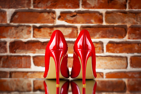 Red high heels on the red brick wall backgroundの写真素材