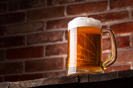 Mug of a beer on the red brick wall backgroundの写真素材