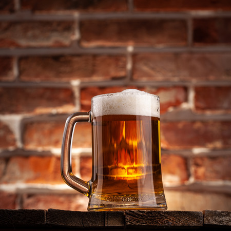 Mug of a beer on the red brick wall backgroundの写真素材