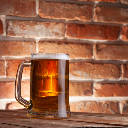Mug of a beer on the red brick wall backgroundの写真素材