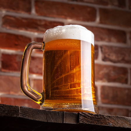 Mug of a beer on the red brick wall backgroundの写真素材
