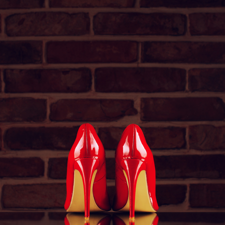 Red high heels on the red brick wall backgroundの写真素材