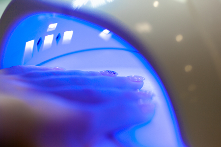 UV lamp gel polish manicure process in a beauty salonの写真素材