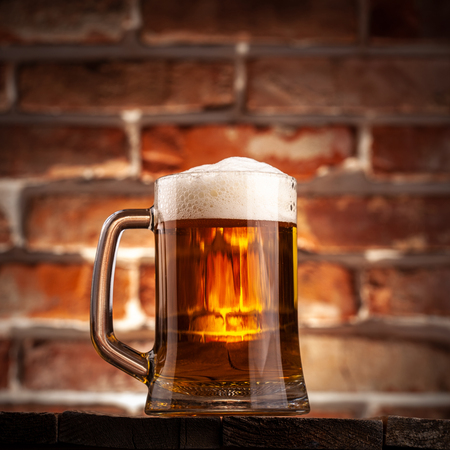 Mug of a beer on the red brick wall backgroundの写真素材