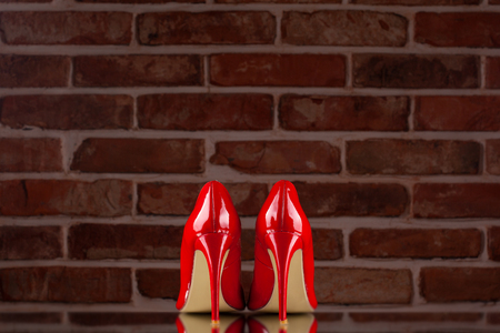 Red high heels on the red brick wall backgroundの写真素材