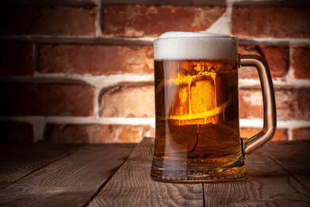 Mug of a beer on the red brick wall backgroundの写真素材