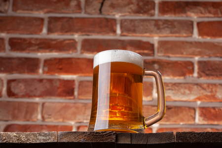 Mug of a beer on the red brick wall backgroundの写真素材