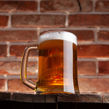 Mug of a beer on the red brick wall backgroundの写真素材
