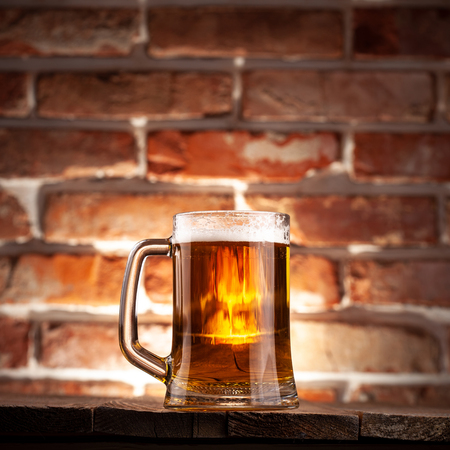 Mug of a beer on the red brick wall backgroundの写真素材