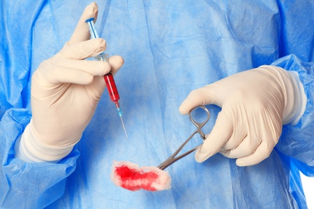 syringe and clamp with swab in the hand of the surgeon during a surgery