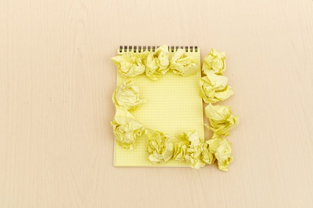 Notebook and crumpled paper on wooden tableの写真素材