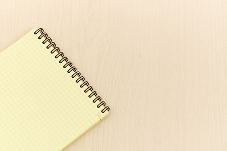 yellow note book with lots of room for your text or image on a wooden deskの写真素材