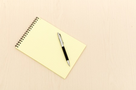 yellow note book with lots of room for your text or image on a wooden deskの写真素材