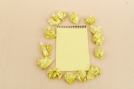 Notebook and crumpled paper on wooden tableの写真素材