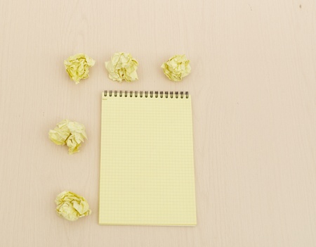 Notebook and crumpled paper on wooden tableの写真素材