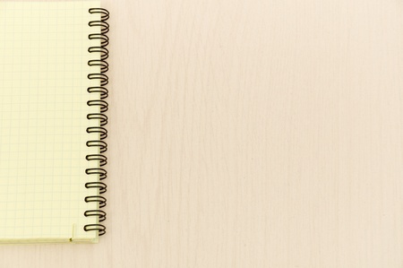 yellow note book with lots of room for your text or image on a wooden deskの写真素材