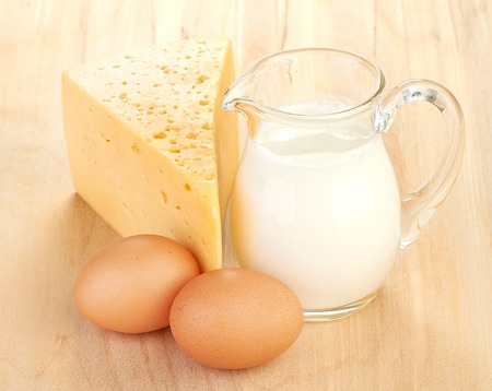 Big piece of cheese, glass jug with milkの写真素材