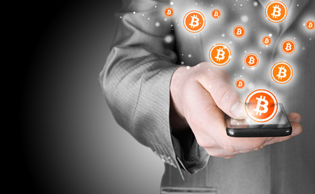 Hand with mobile smart phone and bitcoin symbolの写真素材