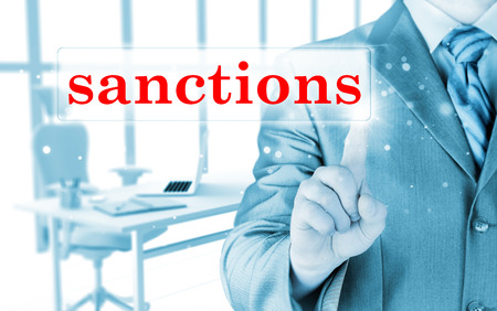 businessman pressing sanctions button on virtual screensの写真素材