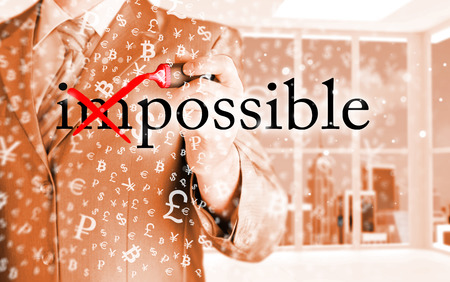 Businessman Hand turning the word Impossible into Possible with red marker