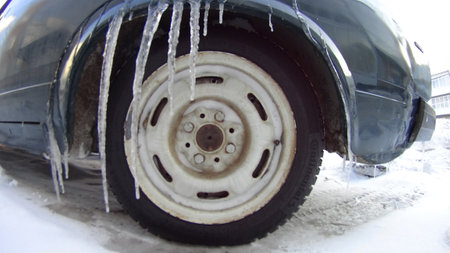 Frozen car wheel on a snowy road in winter. Cold weather.の写真素材