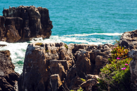 A peaceful ocean scene with shimmering blue water stretching to the horizon, rocky formations in the...