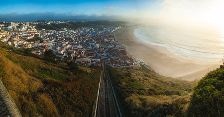 An expansive coastal town view with white houses and red roofs stretching along a golden sandy beach