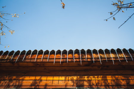 icicles on the roof of a wooden house in spring in Siberiaの写真素材