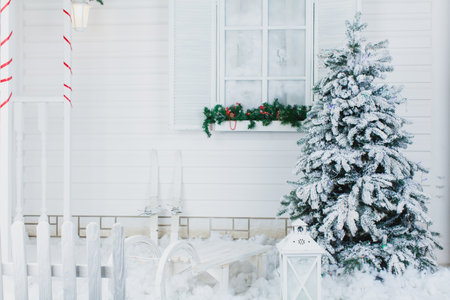 A wooden sleigh at a Xmas tree at a white wooden houseの写真素材