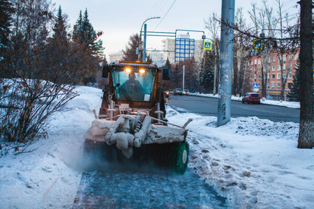 snow removal machine at work on sidewalkの写真素材
