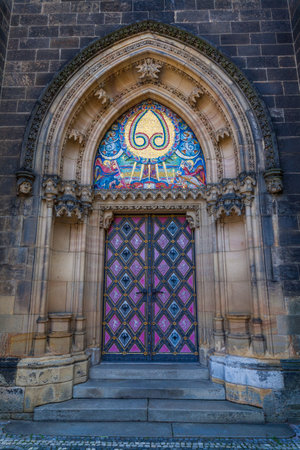 A detailed view of an arched entrance featuring a colorful mosaic above a double door with a diamond pattern, set into a textured stone wall.の写真素材