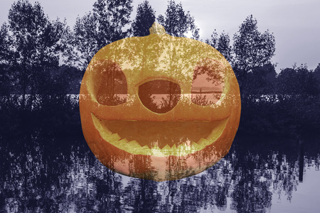 Double exposure of halloween pumpkin with swamp background.の写真素材