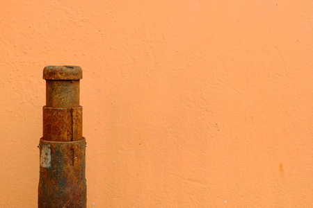 Close up Old Manual Jack with Orange Painting Concrete Wall. (Selective Focus on Top)