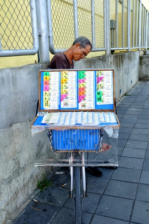 Unidentified Lottery Ticket Seller Sitting on Footpath in Bangkok, Thailand.のeditorial素材