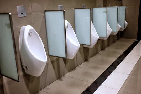 Close-up Row of White Ceramic Urinals in Public Toilet.