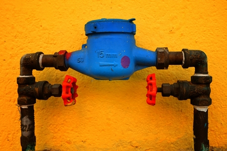 Old Blue Water Meter With Yellow Painted Concrete Wall Background.の写真素材