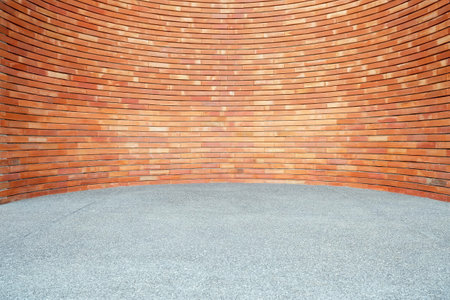 Red Brick Wall Background in Curved Style with Sand Pavement.の写真素材
