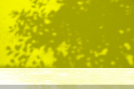 Yellow Stucco Table with Bokeh of Tree Shadow on Concrete Wall Texture Background, Suitable for Cosmetic Product Presentation Backdrop, Display, and Mock up.の写真素材