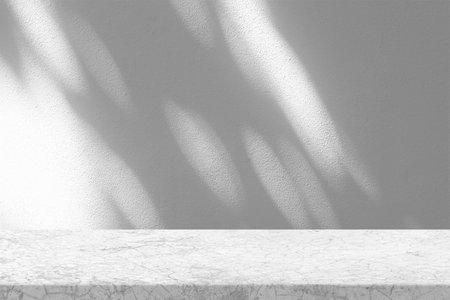 Stucco Table with White Stucco Wall Texture Background with Bokeh Light Beam and Shadow, Suitable for Product Presentation Backdrop, Display, and Mock up.の写真素材