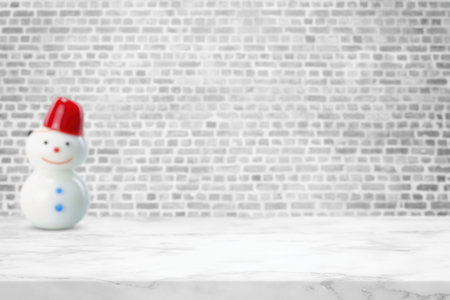 White Marble Table (Selective Focus on Surface) with Blurred Brick Wall Background with Snowman Doll, Suitable for Product Presentation Backdrop, Display, and Mock up in Christmas Concept.の写真素材