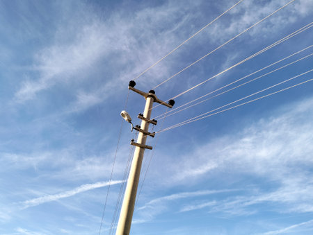 High voltage post with blue sky and white clouds in the background.