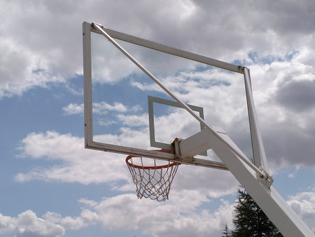 Basketball hoop against blue sky with white clouds. Close-up.