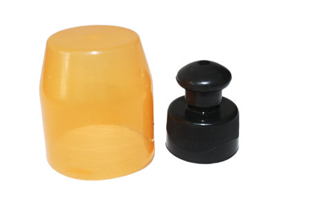 Yellow plastic bottle with black cap and black cap isolated on white backgroundの写真素材