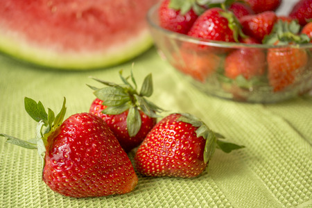 Red fruits  Three strawberries in Huelva on a green tablecloth  Background watermelon の写真素材