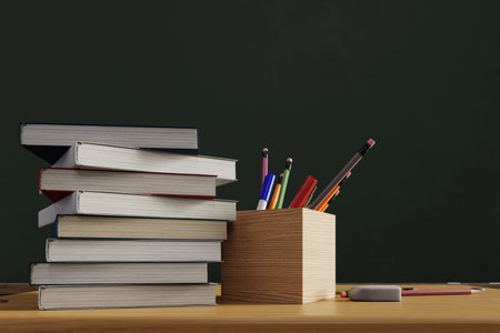 A pencil case and stacked textbooks with a blackboard in the background, 3d rendering