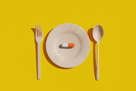 A nutritional pill is placed on a plate with a fork and spoon on either side. 3d renderingの写真素材