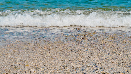 Summer beach sand, blue waves and white foam